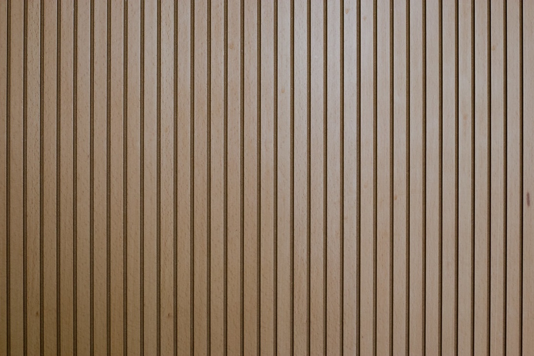 Modern innervägg med vertikala träribbor som skapar ett rytmiskt mönster och tillför värme.